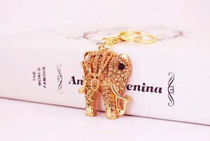 Close-up of a golden elephant keychain featuring amber rhinestones on a book edge