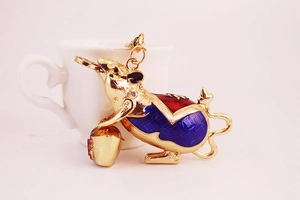 Close-up of golden mouse keychain with blue enamel, sparkling rhinestones and gold ingot