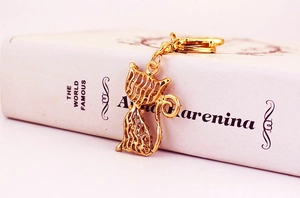Détail d'un pendentif chat évidé doré avec motif de maille fine sur un livre blanc