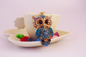 Détail du pendentif hibou orné de cristaux strass bleus et d'une finition dorée mate