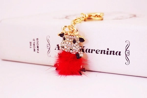 Detail of red pompom ox keychain with sparkling rhinestones on an open book cover