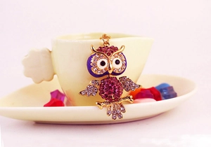 Detail of colorful crystal owl keychain featuring rose rhinestones on a coffee cup