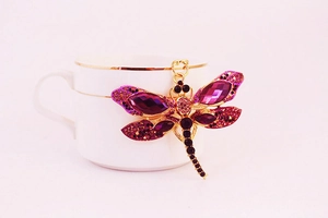 Détail d'un porte-clés libellule avec strass violets accroché à une tasse