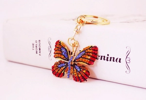 Detail of golden butterfly keychain with colorful rhinestones on a white book prop