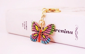 Detail of a gold butterfly keychain featuring vibrant colorful rhinestones on a white background