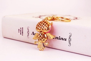 Detailed back view of a golden owl keychain with floral hollow patterns and round clasp
