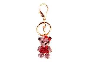 Détail d'un porte-clés ours étincelant avec des cristaux rouges et un petit nœud