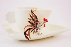 Detailed close-up of a sparkling rhinestone rooster keychain on a white ceramic cup