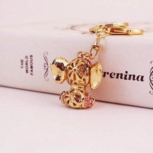 Golden elephant keychain with pink rhinestones and hollow patterns on decorative book