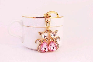 Detail von süßem Kristall-Katzen-Schlüsselanhänger mit rosa Steinen auf einer Tasse