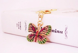Detail of a butterfly keychain with colorful rhinestones on a white book background