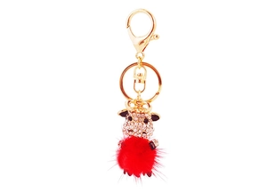 Detailed close-up of a golden cow keychain with white rhinestones and a soft red pompom