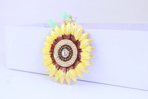 Detail of sunflower pendant with yellow enamel petals and sparkling rhinestone center