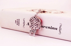 Detail view of silver dog keychain featuring hollow clover pattern on the back side