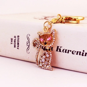 Porte-clés chat scintillant avec finition dorée et strass sur fond de livre décoratif