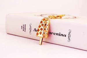 Detailed close-up of popsicle keychain with golden clover pattern and pink crystals