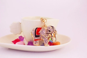 Close-up of golden elephant keychain with sparkling crystals and enamel details on a cup