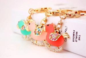 Close-up of golden rocking horse keychains with colorful crystals in mint, pink, and orange