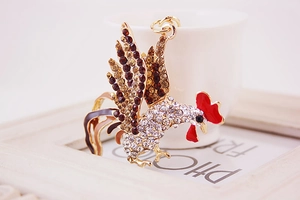 Macro detail of a rooster keychain featuring gold plating and shimmering rhinestones