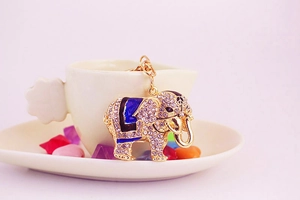 Detailed view of elephant keychain with white rhinestones and blue enamel on a white cup