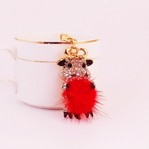 Charming golden ox keychain with sparkling rhinestones and a soft red pompom accessory