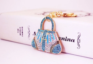 Detail of a sparkling gold handbag keychain with blue rhinestones and a lobster clasp