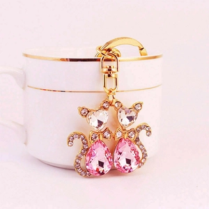 Süßer Katzen-Schlüsselanhänger in Gold mit rosa Kristallen an einer Tasse hängend