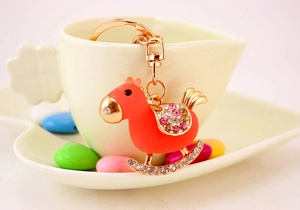 Detailed view of an orange rocking horse keychain with sparkling crystal embellishments