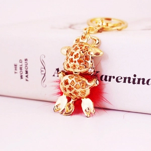 Golden zodiac ox keychain with hollow patterns and red pompom on a white book