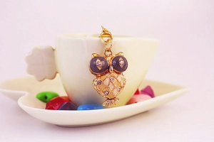 Detail of owl pendant featuring gold metal, purple enamel and sparkling rhinestones