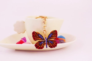 Detail of colorful butterfly keychain with red and blue rhinestones on a gold base