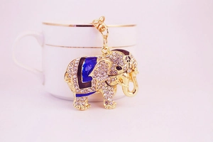 Close-up of sparkling elephant keychain with white rhinestones on a white porcelain cup