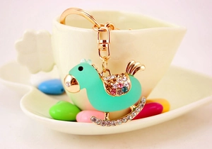Detail of mint green rocking horse keychain with crystal rhinestones on a ceramic dish