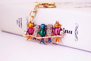 Detailed close-up of crystal birds on a golden branch keychain with shiny rhinestones