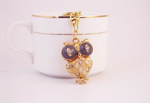 Detailed close-up of a purple rhinestone owl keychain on a decorative white cup