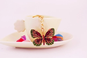 Detail of butterfly keychain with vibrant red, green, and champagne rhinestones on gold frame