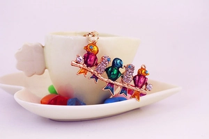Detailed close-up of colorful rhinestone-studded birds on a golden branch keychain