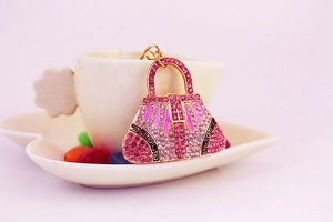 Detailed close-up of a luxury gold-plated handbag keychain with sparkling pink rhinestones