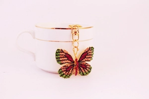 Detailed close-up of a colorful rhinestone butterfly keychain hanging on a ceramic cup