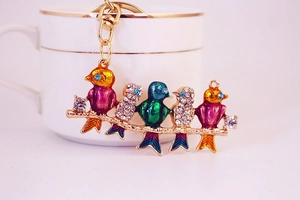 Macro shot of colorful enamel birds on a branch with crystal rhinestones for a keychain