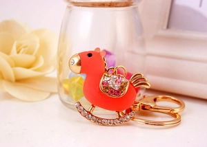 Macro shot of orange crystal rocking horse keychain with pink rhinestones on horse base