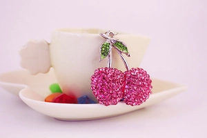 Macro detail of sparkling pink rhinestone cherry keychain with green crystal leaves