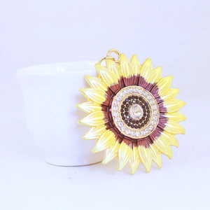 Fashion sunflower keychain with yellow petals and crystal center on a white cup