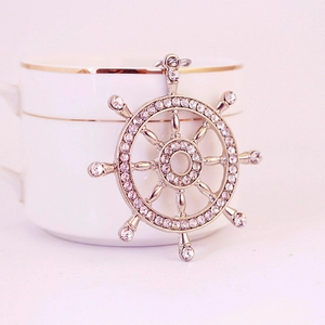 Pendentif gouvernail en argent étincelant avec strass sur le bord d'une tasse blanche