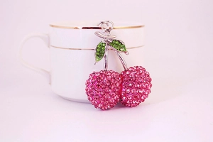Detailed view of pink rhinestone cherry pendant with green leaves and silver metal ring