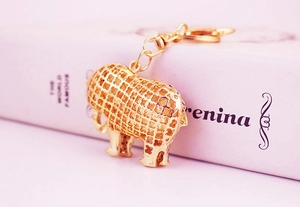 Macro view of a gold elephant keychain with hollow mesh craft leaning on pink books