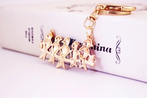 Detail of five golden birds on a branch keychain with smooth metal back and clasp
