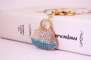 Detailed close-up of a gold-plated handbag keychain with blue and white crystals
