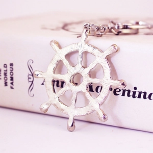 Porte-clés nautique en métal argenté avec gouvernail de navire sur un livre blanc