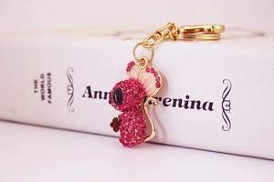 Detail of pink crystal mouse keychain with golden lobster clasp on a book